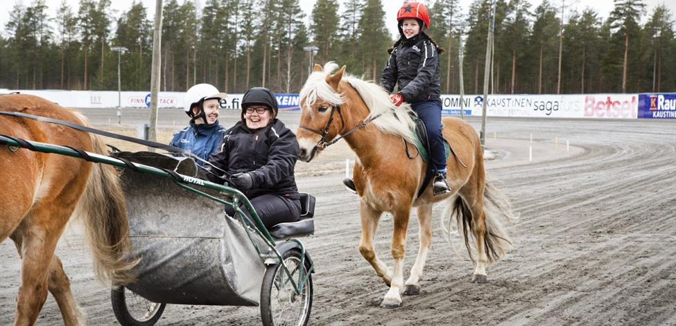 Kuvassa hevosalan opiskelijat ajavat ravihevosen kärryissä.